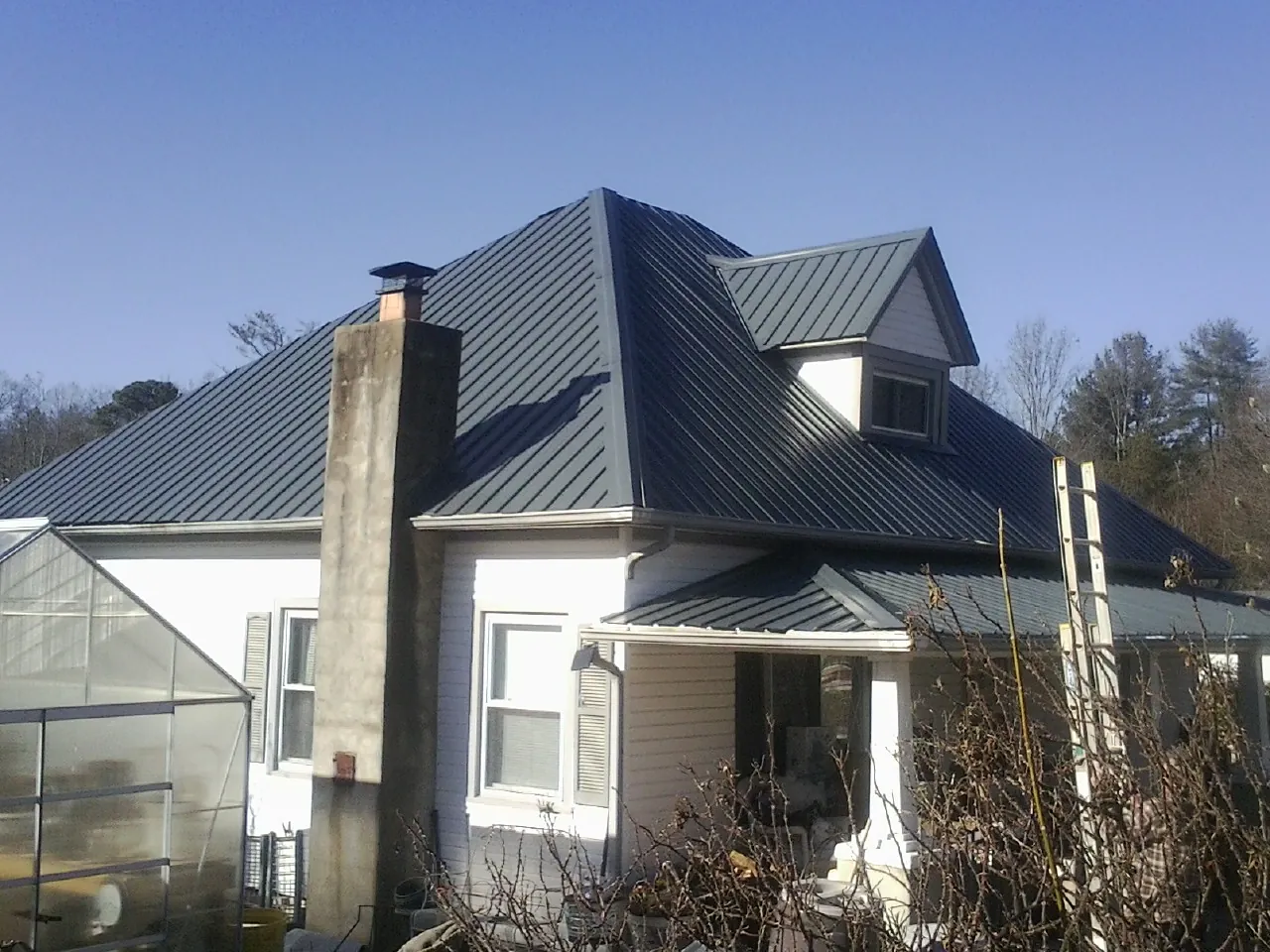 Dark blue standing seam metal roof on a white farmhouse with dormer — Slate & Tile Roof Repair by Roofing Brothers in Dauphin