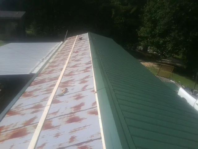 Old rusted panels beside newly installed green metal roofing — Wind Damage Roof Repair by Roofing Brothers in Dauphin