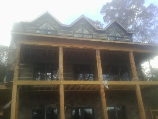 Dormers and porch framing on a large log home under construction — Roof Coating work by our crew in Dauphin