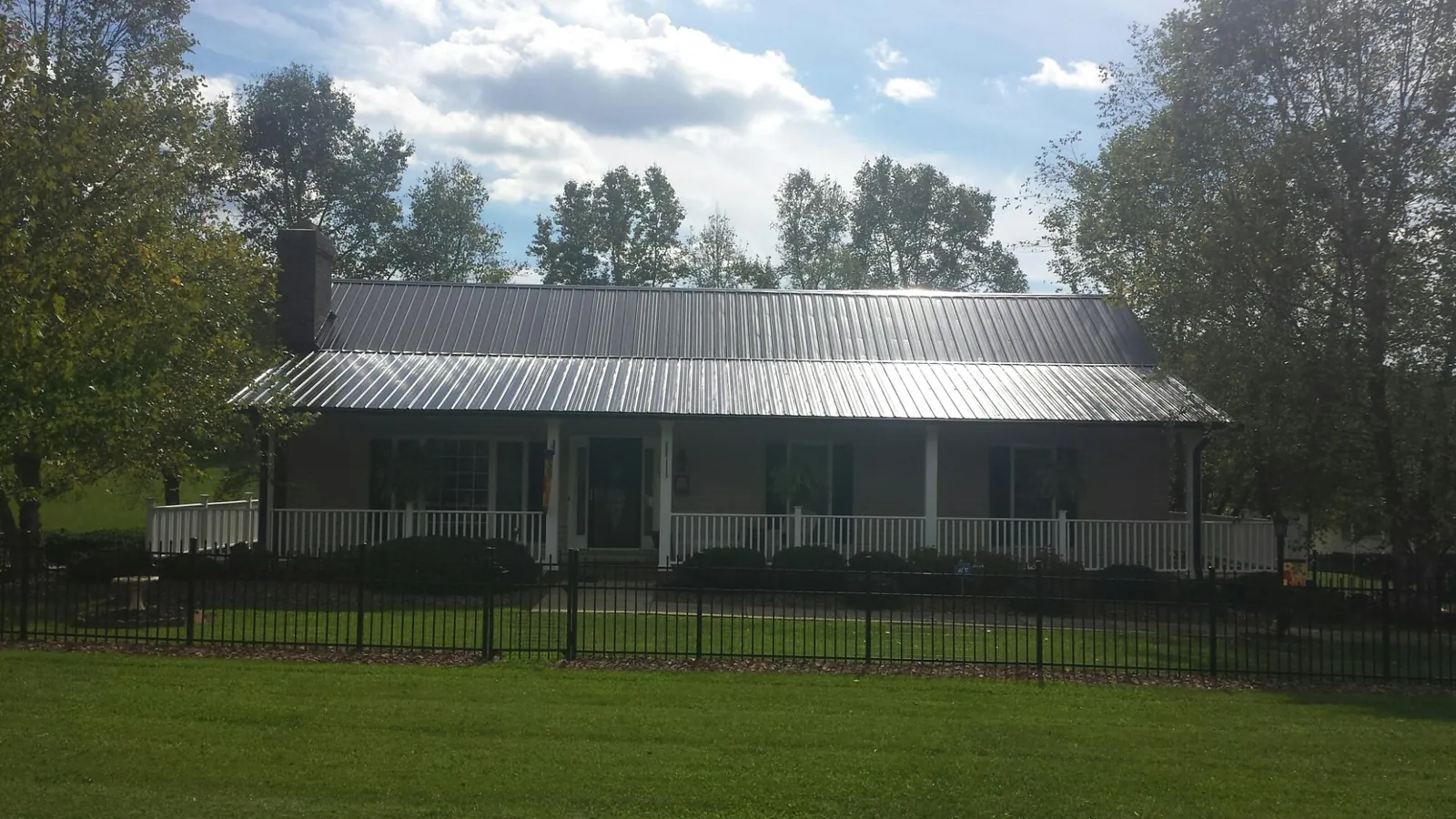 Gray metal roof on a brick ranch with a full width front porch — Gutter Guard Installation work by our crew in Dauphin