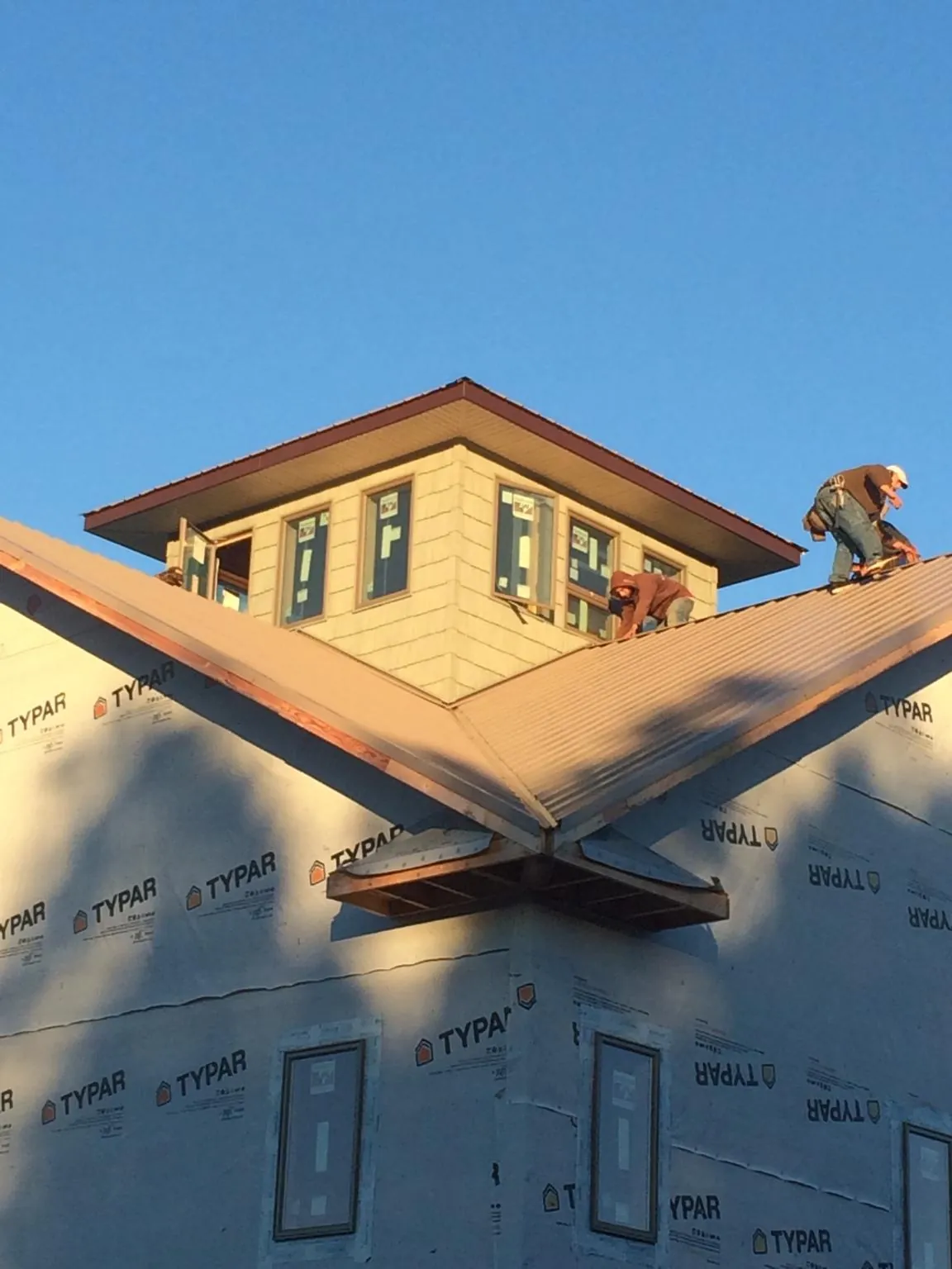 Roofers working around a rooftop cupola on a new metal roof at sunset — Roof Waterproofing in Dauphin by Roofing Brothers
